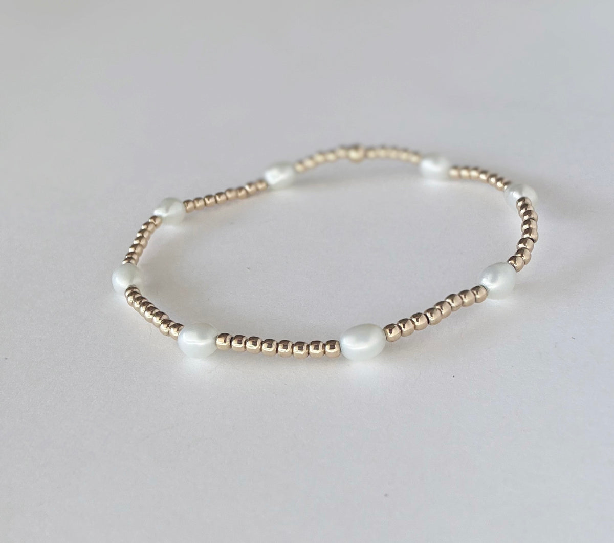 The Junie bracelet laid flat, showing gold beads and freshwater pearls