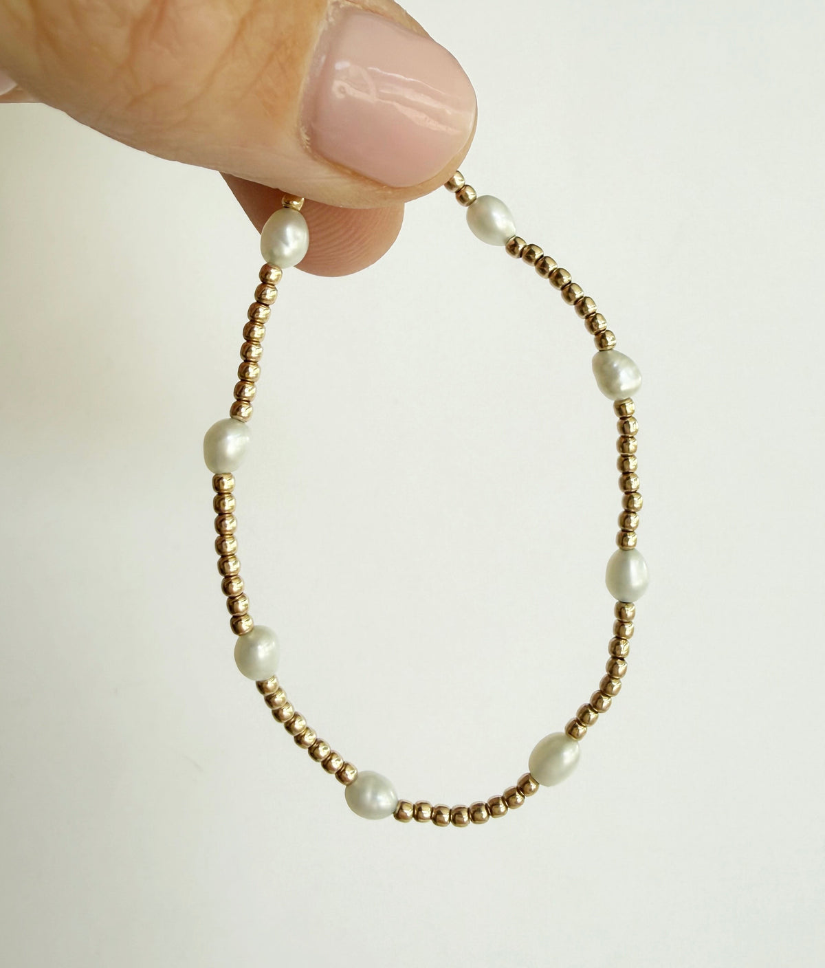The Junie bracelet held between fingers